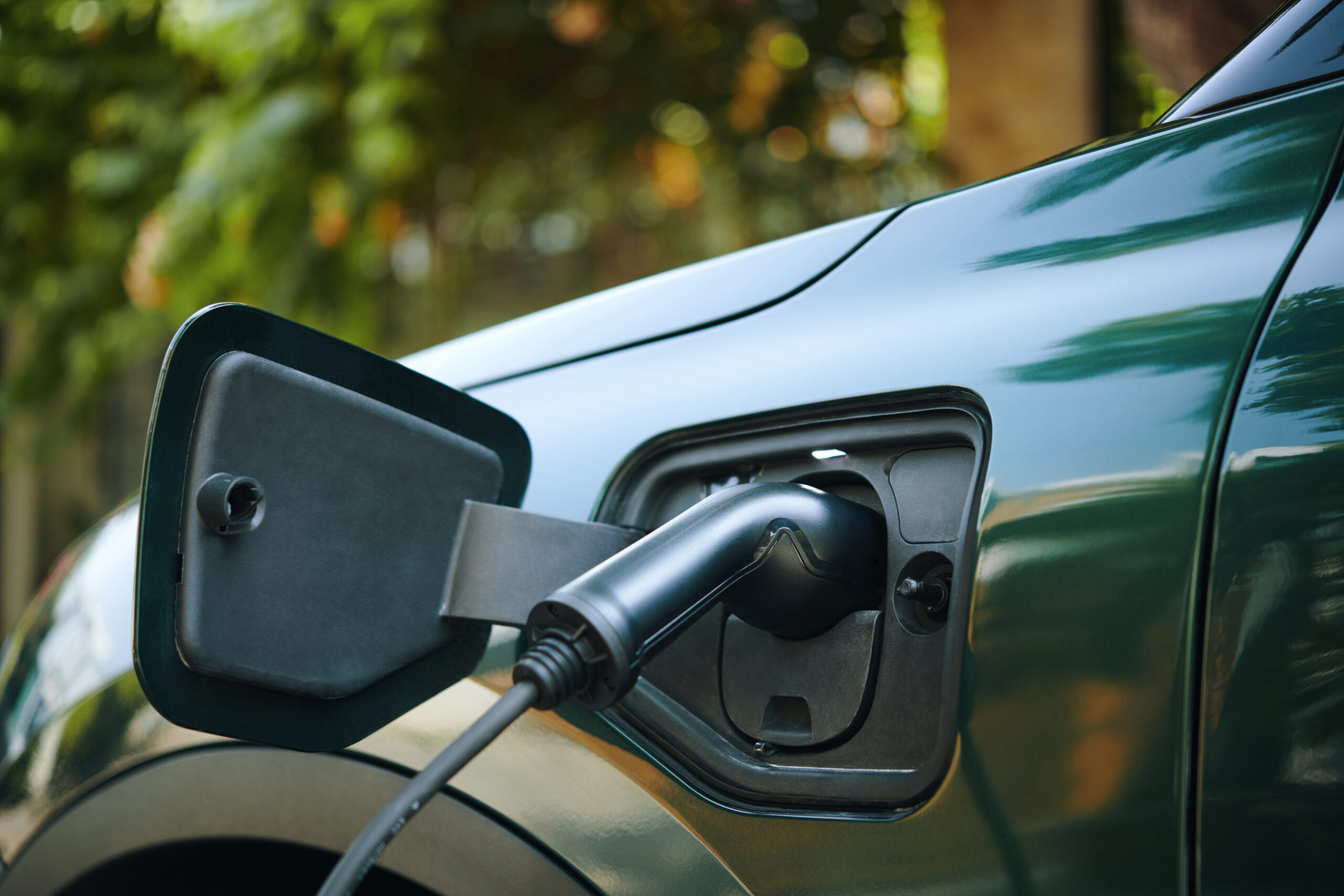 Vehículo eléctrico conectado a una estación de carga rápida mientras recarga su batería en un punto de carga moderno.